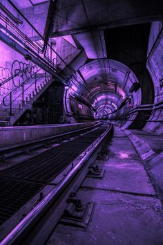 an underground tunnel with tracks and graffiti on the walls