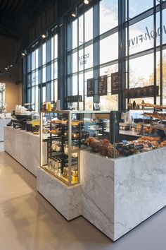 the inside of a restaurant with marble counter tops and glass walls, along with lots of food