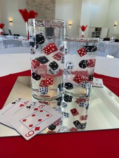 two glasses with dice and playing cards on them