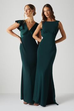 two women in long dresses standing next to each other, one wearing a green dress