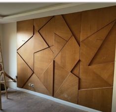 an unfinished room with wood paneling on the wall and ladders in front of it