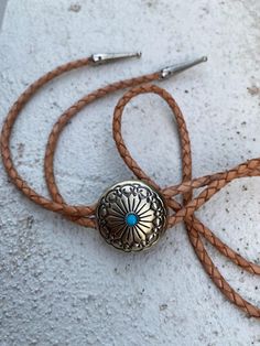 Western Bolo Tie.  This bolo has brushed brass finish, kind of a champagne gold (not yellow gold), with a small turquoise, finished with silver tips.  Fully adjustable on real a natural/tan leather cord.  Perfect for a western wedding or race day! 🐎  Unisex, can be a shared piece with your partner!  🔅 follow us on Instagram @bolowest_ Adjustable Gold Western Bolo Ties, Gold Western Bolo Tie, Adjustable Gold Concho Jewelry, Adjustable Vintage Hand Tooled Bolo Tie, Vintage Adjustable Hand Tooled Bolo Tie, Western Style Brown Jewelry With Adjustable Length, Brown Western Jewelry With Adjustable Length, Brown Western Jewelry With Adjustable Cord, Brown Concho Bolo Tie Lariat