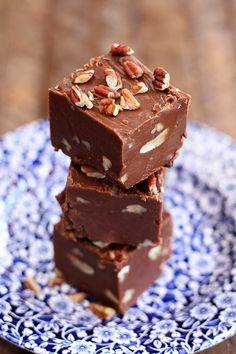 three pieces of fudge chocolate stacked on top of each other with pecans in the background