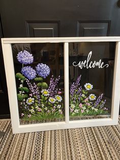 two windows with flowers painted on them and the words welcome are in front of each window