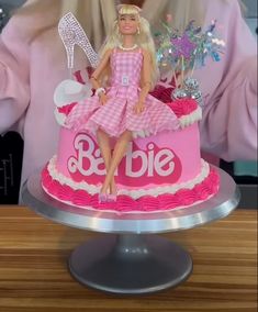 a barbie doll sitting on top of a pink cake