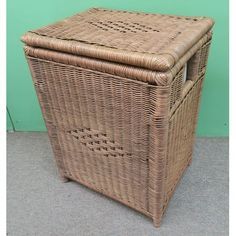 a brown wicker basket with lid sitting on the floor next to a green wall