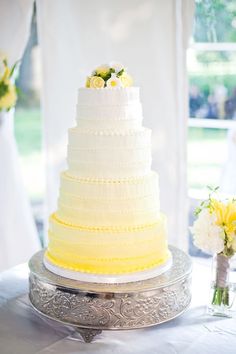 a white and yellow wedding cake sitting on top of a table