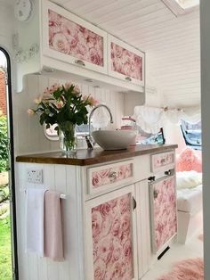 a pink and white kitchen with flowers on the counter