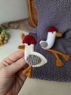 a crocheted bird with a red hat on it's head is being held by a hand