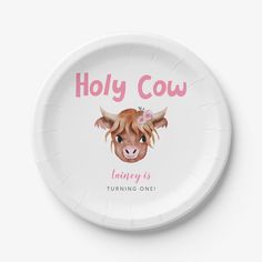 a paper plate with an image of a cow's face on it, and the words holly cow is turning one