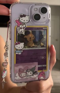 someone holding up their cell phone case with hello kitty stickers on the front and back