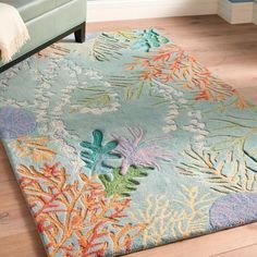 a blue rug with colorful corals and seaweed on it in a living room