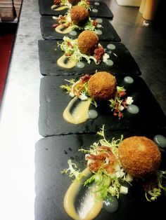 a row of black plates topped with different types of food on top of each other