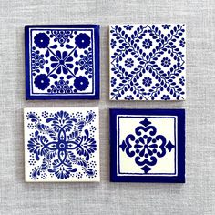 four blue and white tiles with designs on them