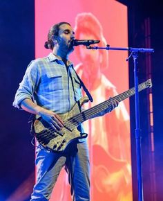 a man standing in front of a microphone and holding a guitar on top of a stage