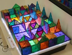 an array of colorful origami blocks sitting on top of a white table in front of a mirror