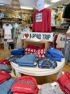 clothing and hats are on display in a store, with the sign reading road trip