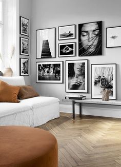 a living room filled with lots of pictures on the wall above a white couch and coffee table