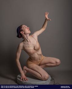 a woman is sitting on top of a round object with her hands in the air