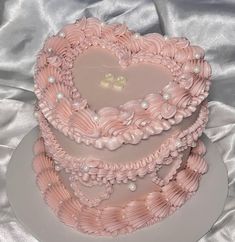 a three tiered cake with pink icing and pearls on it's sides