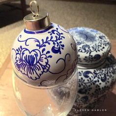 two blue and white ornaments sitting on top of a glass vase next to each other