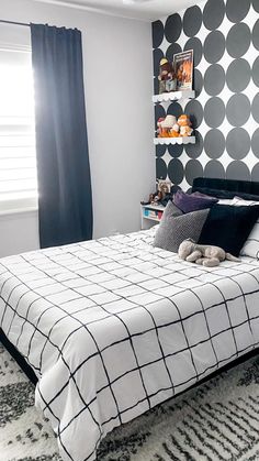 a black and white bedroom with polka dots on the wall behind the bed, along with an area rug