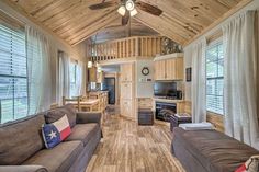 a living room filled with furniture next to windows and a ceiling fan in the corner