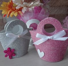 two pink and silver cupcakes sitting next to each other on top of a table