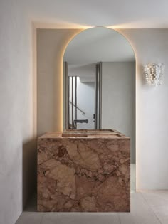 a marble counter top in front of a mirror and light fixture with lights on it