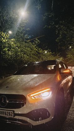 a car parked on the side of the road at night with its headlights turned on