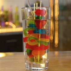 a glass filled with gummy bears sitting on top of a table