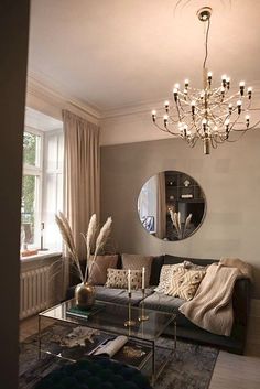 a living room filled with furniture and a chandelier hanging from the ceiling next to a window