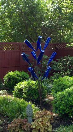 a blue glass sculpture in the middle of a garden