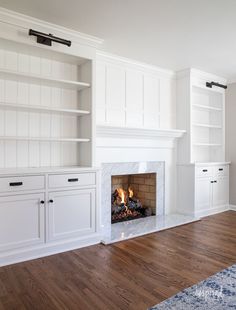 an empty living room with a fireplace and built - in bookshelves