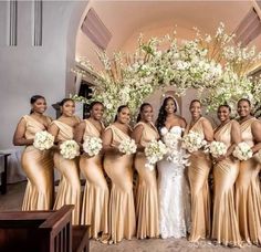 a group of women standing next to each other in front of a white flower arch