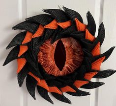 an orange and black wreath with a large eye