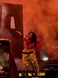 a woman standing on top of a stage holding a cell phone up to her ear