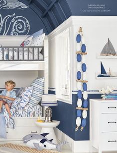 a young boy sitting on top of a bunk bed in a blue and white room