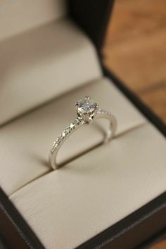 an engagement ring in a box on a wooden floor