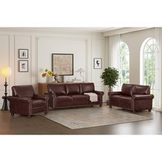 a living room with brown leather furniture and large windows in the wall behind it is an area rug that matches the hardwood flooring