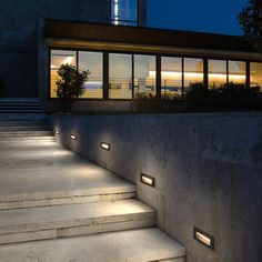 some steps that have lights on them in front of a building with windows and stairs leading up to it