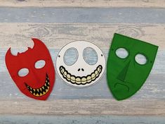 three masks with faces painted on them, one green and one red are sitting next to each other