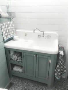 a white sink sitting next to a green cabinet in a bathroom on top of a black and white checkered floor