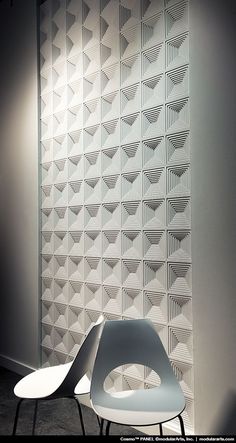 two chairs sitting next to each other in front of a wall with geometric designs on it