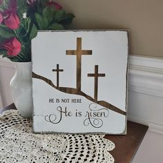 a wooden sign with the words he is not here and a crucifix on it