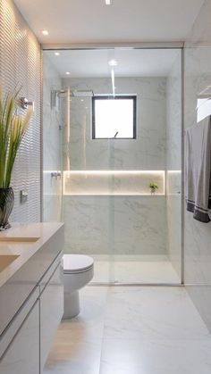 a modern bathroom with white marble walls and flooring, along with a glass enclosed shower stall