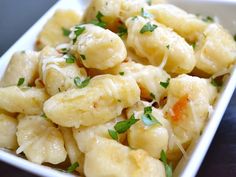 a white bowl filled with pasta and garnished with parsley