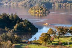 an aerial view of a lake surrounded by trees and hills with a boat in the water