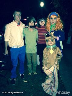 a group of people standing next to each other wearing costumes and wigs at night