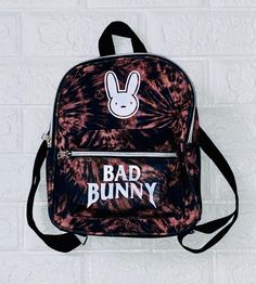 "FOR MORE BAD BUNNY ITEMS FOLLOW THE LINK BELOW https://www.etsy.com/shop/5pointproductions?ref=search_shop_redirect 🚨 PLEASE READ CAREFULLY Throw on your Bad Bunny Mini Backpack / Bookbag as a great way to keep your belongings handsfree. This is great for the beach, concerts, games, amusement parks or to run errands on the weekends! Put all your belongings in it and head out to Bad Bunny El Ultimo Tour Del Mundo (EUTDM) concert. 🚨Backpacks are available in: White - Black - Tie Dye Choice of d Bunny Items, Mini Bookbag, Bunny Backpack, Cute Surprises, Cotton Sleepwear, Amusement Parks, Black Tie Dye, Bad Bunny, Mini Backpack